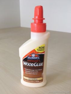 a bottle of wood glue sitting on top of a wooden table next to a white wall