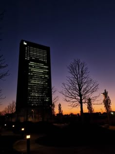 a tall building lit up at night with trees in the foreground