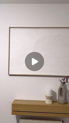 a wooden table topped with vases next to a wall mounted art piece on the wall