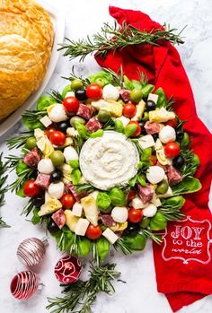 a christmas wreath made out of fresh vegetables and meats on a marble counter top