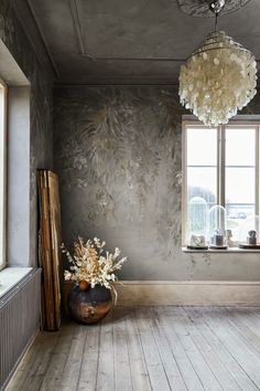 a vase with flowers sitting in front of a window on a wooden floor next to a radiator