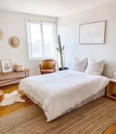 a bedroom with white walls and wooden floors