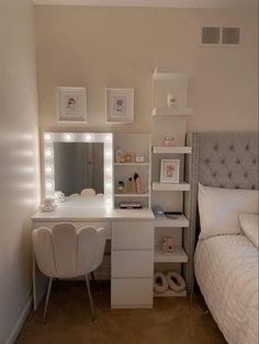 a bedroom with a bed, desk and mirror in the corner that has lights on it