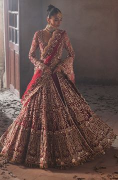 a woman in a red and gold bridal gown standing next to an open doorway