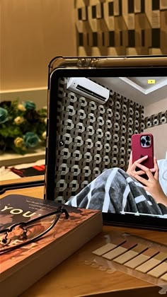 a person is looking at their cell phone while sitting in front of a television screen