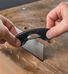 a person using a pair of scissors to cut wood