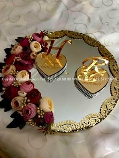 two heart shaped mirrors sitting on top of a white bed covered in pink and purple flowers