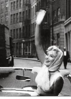 a woman sitting in the back of a car waving