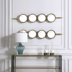 a table with a lamp and some plates on it next to a wall mounted mirror