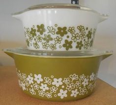 two green and white dishes sitting on top of each other, one has a flowered design