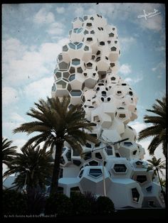 a tall building with lots of windows on top of it's sides and palm trees in the foreground