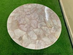 a white marble table sitting on top of a green grass covered floor next to a wall