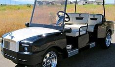 a black and white golf cart parked on the side of the road in front of a field