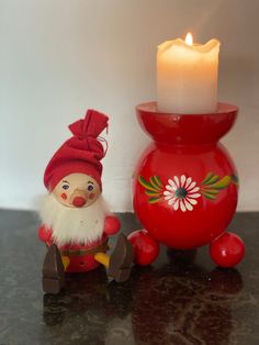 a small red vase with a candle next to it