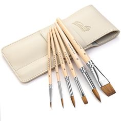 six paint brushes in a leather case on a white surface with an empty wallet behind it