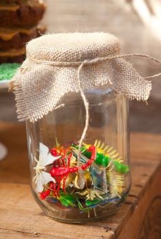 a glass jar filled with lots of different colored candies on top of a wooden table