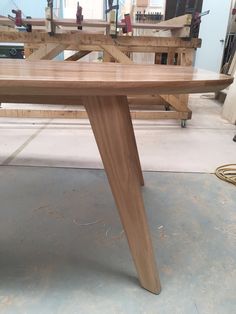 a wooden table sitting on top of a floor next to a pile of wood planks