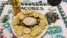 a white plate topped with chips next to a glass of wine and a bottle of beer