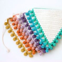 four crocheted squares with tassels on top of each one in different colors