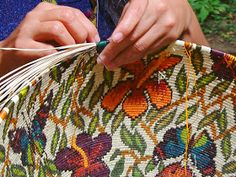 a woman is holding a basket with flowers on it and threading the ends together