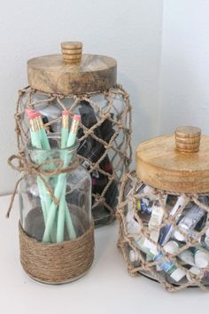 two jars filled with pens and pencils sitting on top of a table next to each other