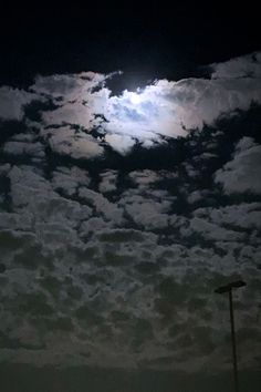 the full moon shines brightly in the cloudy sky above a parking lot at night