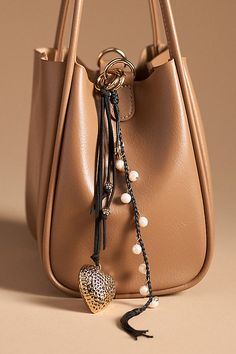 Charming new-trend alert: jewelry for your bag, featuring a boho-inspired heart icon. | Boho Heart Bag Charm by Anthropologie in Black, Women's, Polyester/Plastic/Cubic Zirconia Bag Charms Aesthetic, Handbag Necklace, Diy Bag Charm, Charms Aesthetic, Longchamp Tote Bag, Longchamp Tote, Tassel Bag Charm, Anthropologie Bags, Heart Icon