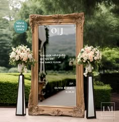 a large mirror sitting next to two vases with flowers on them and an ornate frame