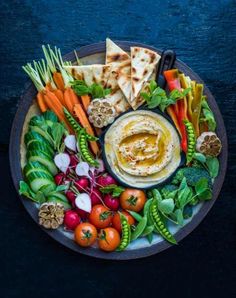 an assortment of vegetables and pita bread on a plate with utensils in the middle