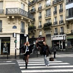 two women crossing the street in front of buildings