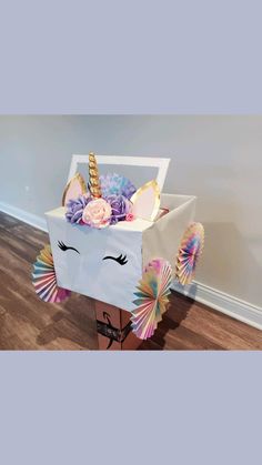 a unicorn themed box with flowers and umbrellas on the floor in front of a wall