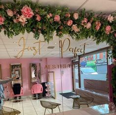 the inside of a salon with pink chairs and flowers