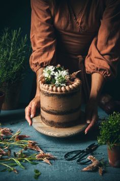 a woman is decorating a cake with flowers