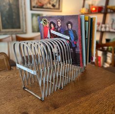 a stack of books sitting on top of a wooden table next to a book rack