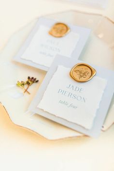 two place cards with gold buttons on them