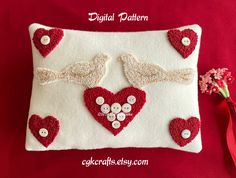 a red and white pillow with two birds on it, surrounded by heart - shaped buttons