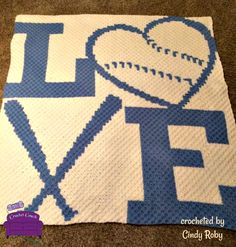 a crocheted blanket with the word love on it and a baseball ball in the middle