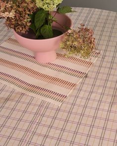 there is a pink bowl with flowers in it on the tablecloths and place mats