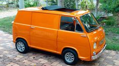 an orange van parked on top of a brick road