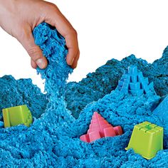 a person is playing with blue sand and plastic blocks