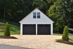 two garages in front of a white fenced in area with trees and grass