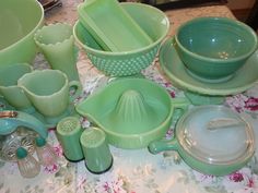 a table topped with lots of green dishes and bowls on top of a table cloth