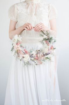 a woman wearing a white dress holding a flower crown