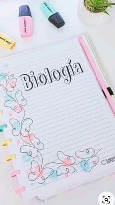 a notebook with the word biologia written on it next to markers and pens