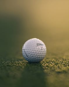 a white golf ball sitting on top of a green grass covered field with the word title written on it