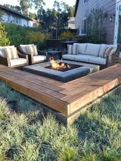 a fire pit sitting on top of a wooden deck next to some grass and bushes