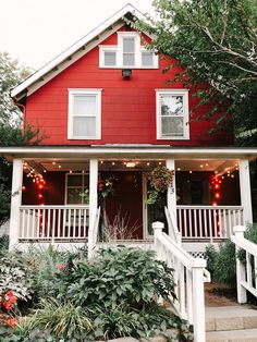 a red house with white porches and lights on it's front door is featured in instagram