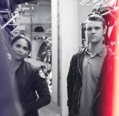 a man and woman standing next to each other in a room full of fire fighter gear