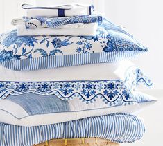 a stack of blue and white pillows sitting on top of each other in front of a basket