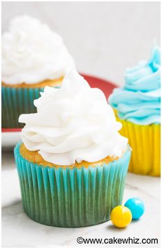 three cupcakes with white frosting and blue icing